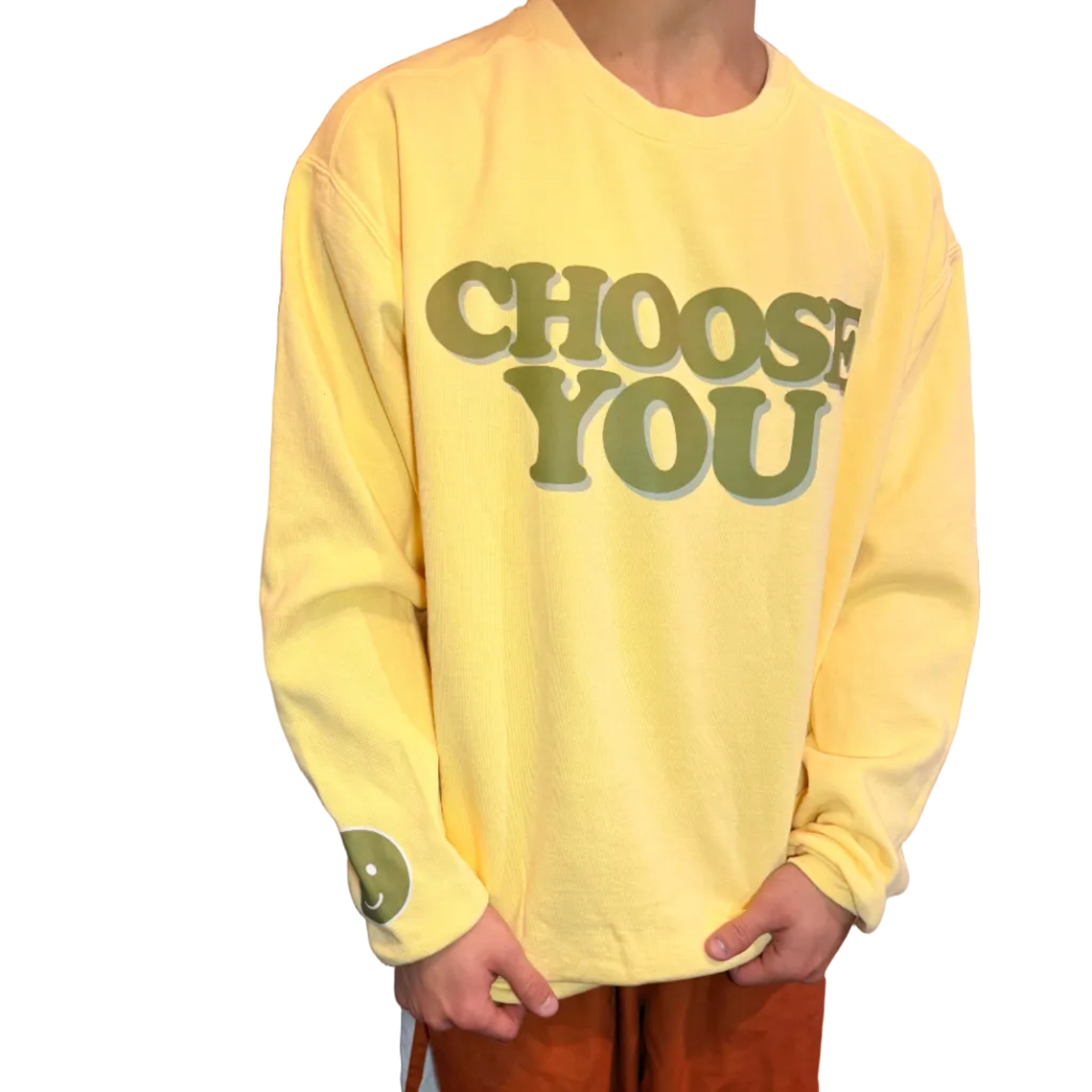 Person wearing a yellow sweatshirt with 'Choose You' text, standing indoors.