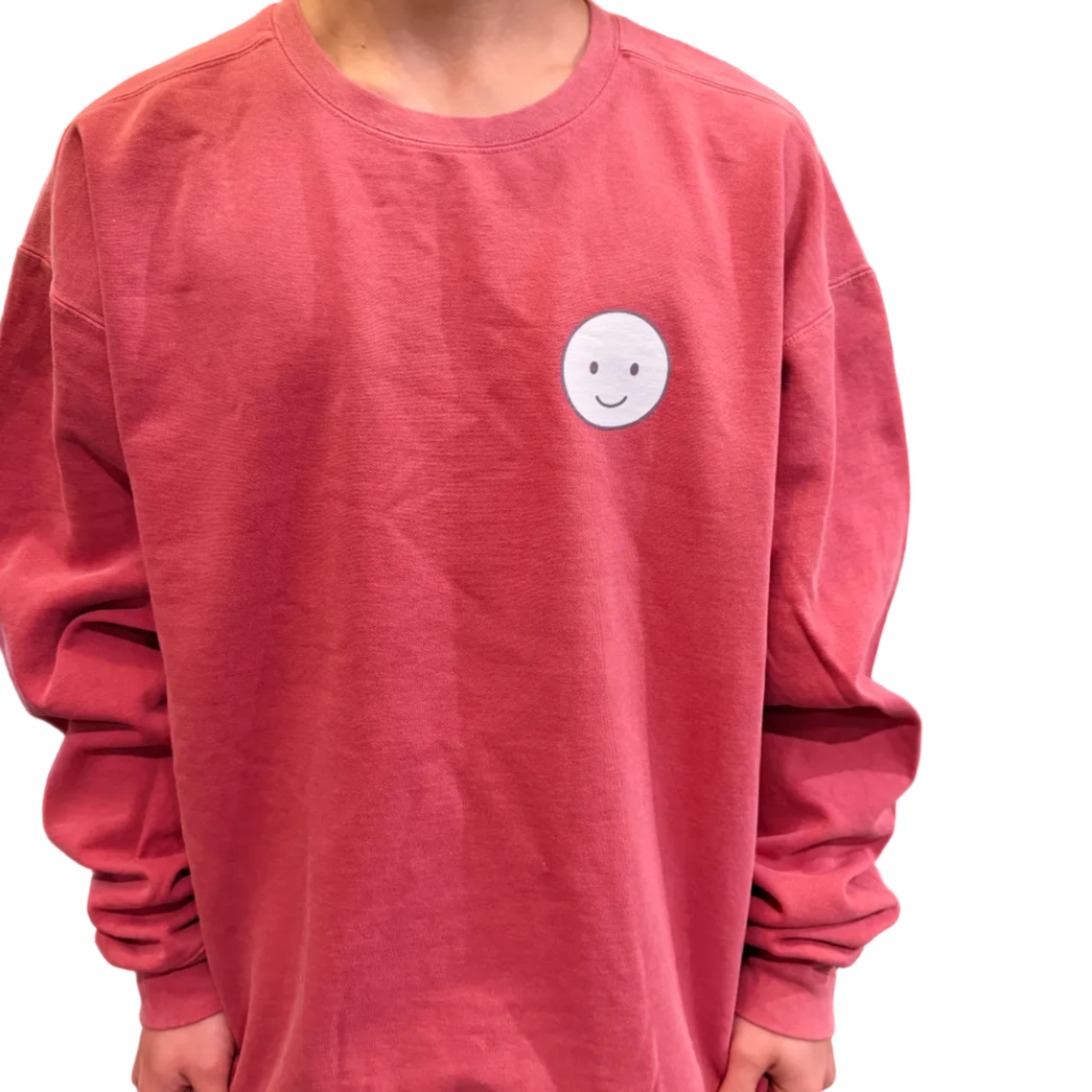 Person wearing a pink sweatshirt with a white smiley face button on a wooden floor.