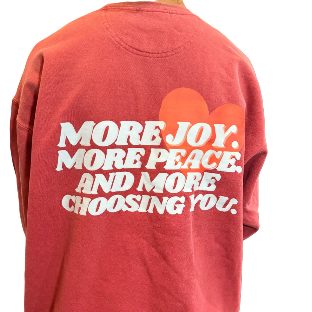 Person wearing a red sweatshirt with motivational text and orange heart design.
