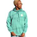 Person wearing a light blue hoodie with a logo, standing in an outdoor setting with trees and a clear sky.