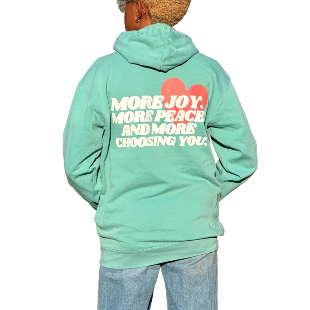 Person wearing a teal hoodie with motivational text in an open field