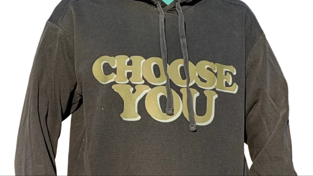 Person wearing a dark gray hoodie with 'CHOOSE YOU' text in a field.