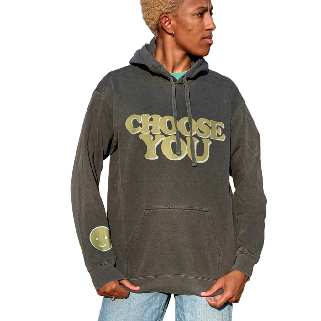 Person wearing a hoodie with 'CHOOSE YOU' text in an outdoor setting