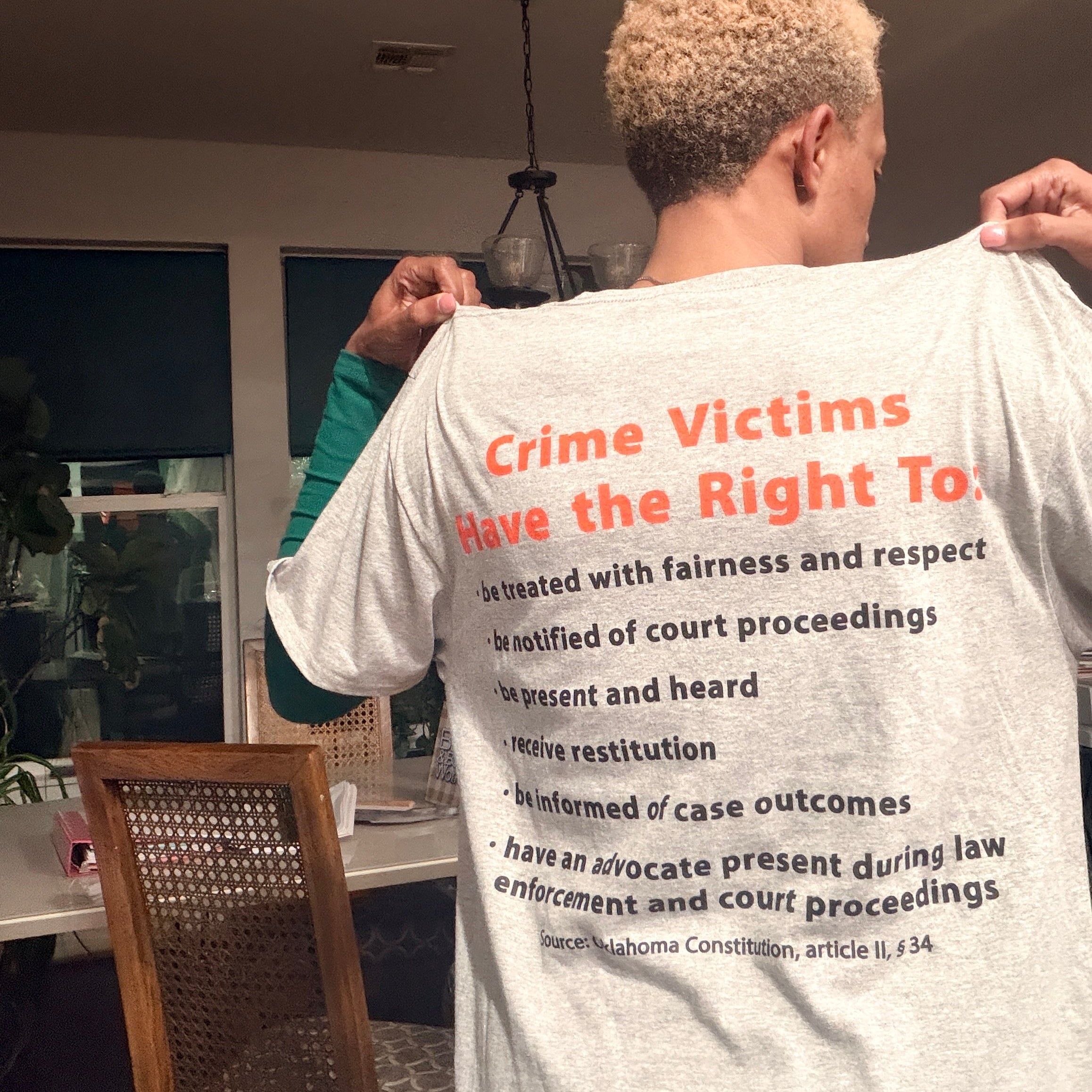 Person wearing a t-shirt with text about crime victims' rights in a room.