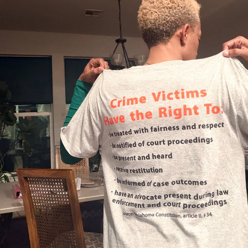 Person wearing a t-shirt with text about crime victims' rights in a room.
