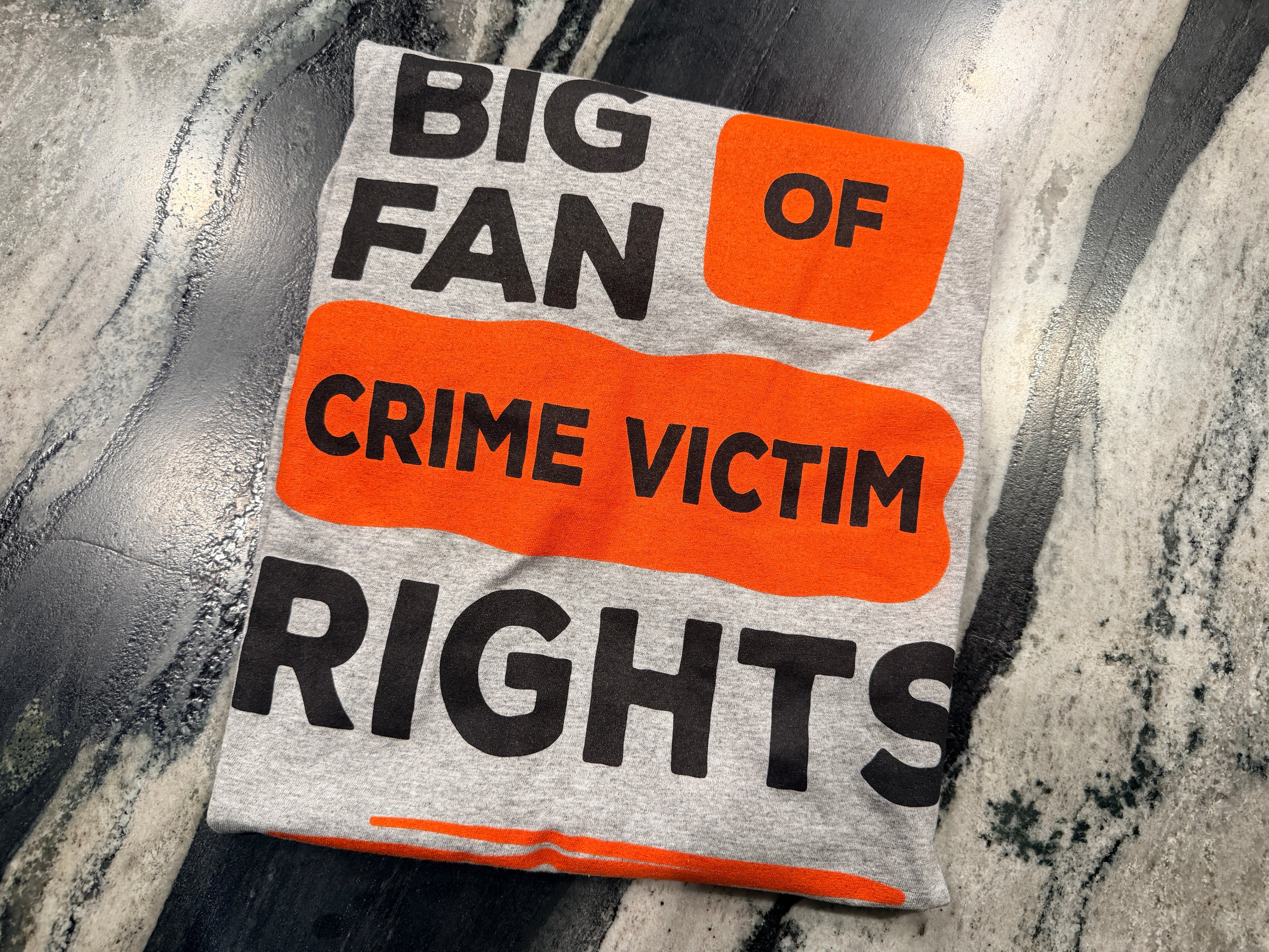 T-shirt with text 'BIG FAN OF CRIME VICTIM RIGHTS' on a textured background
