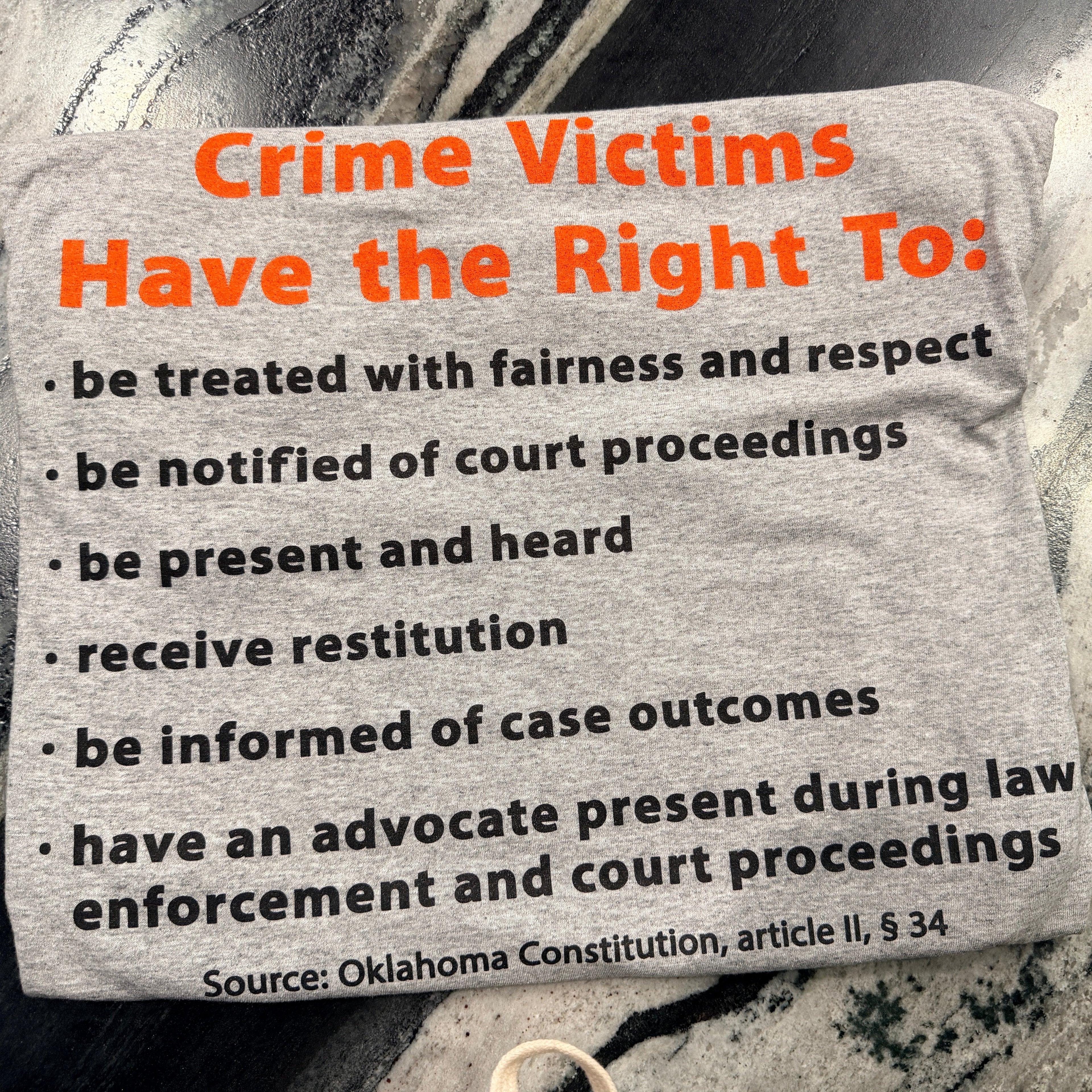Gray sign with text about rights of crime victims on a textured surface