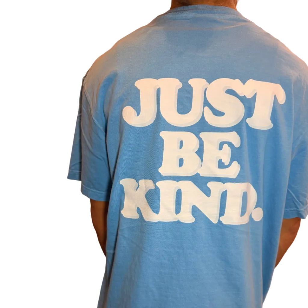 Blue sweatshirt with 'JUST BE KIND' text on a person wearing it indoors.