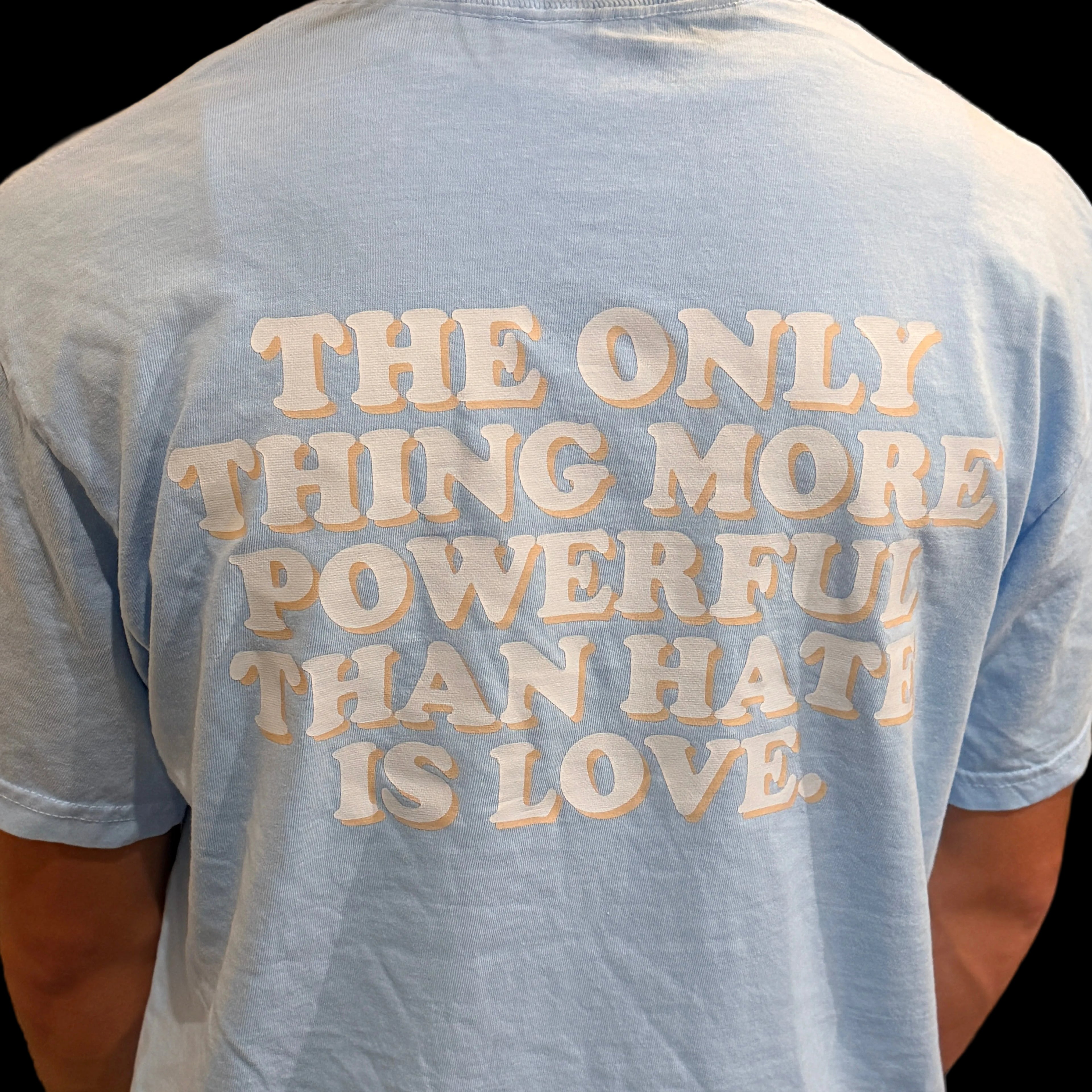 Light blue tee with a quote embroidered on the sleeve.