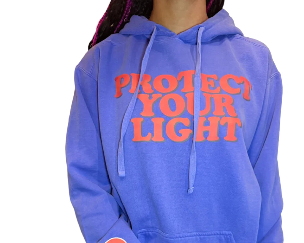 Person wearing a blue hoodie with text and a smiley face on a couch.