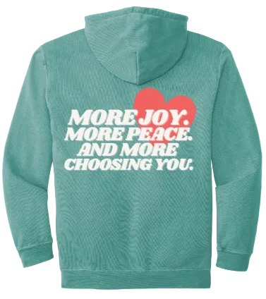 Teal hoodie with motivational text and a red heart on the back against a brown background
