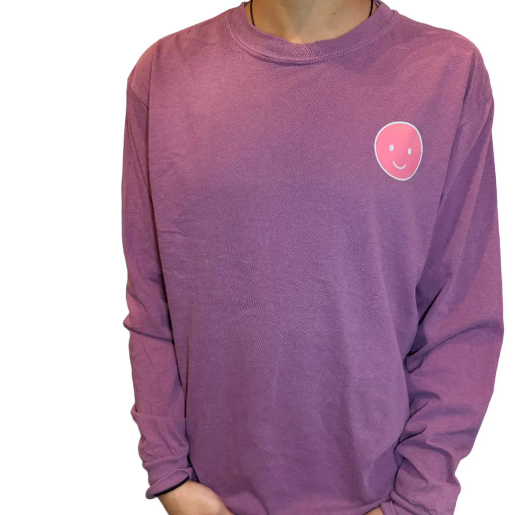 Purple sweatshirt with a smiley face design held by a person indoors.