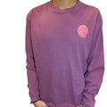 Purple sweatshirt with a smiley face design held by a person indoors.