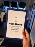 Hand holding a book titled 'Soft Reset' with a blue cover.