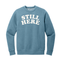Blue sweatshirt with 'STILL HERE' text on a white background
