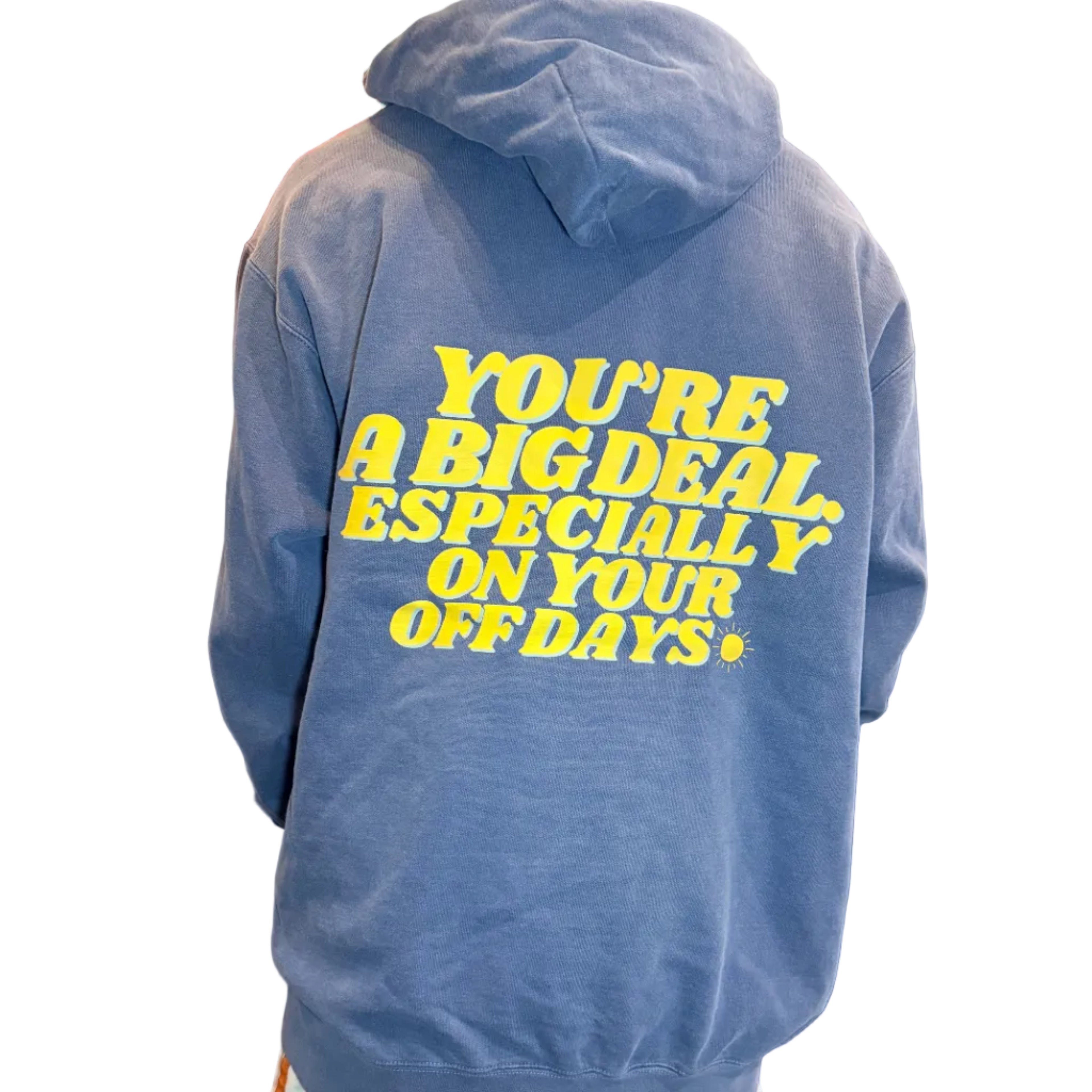 Blue sweatshirt with yellow text worn by a person, with a kitchen background.